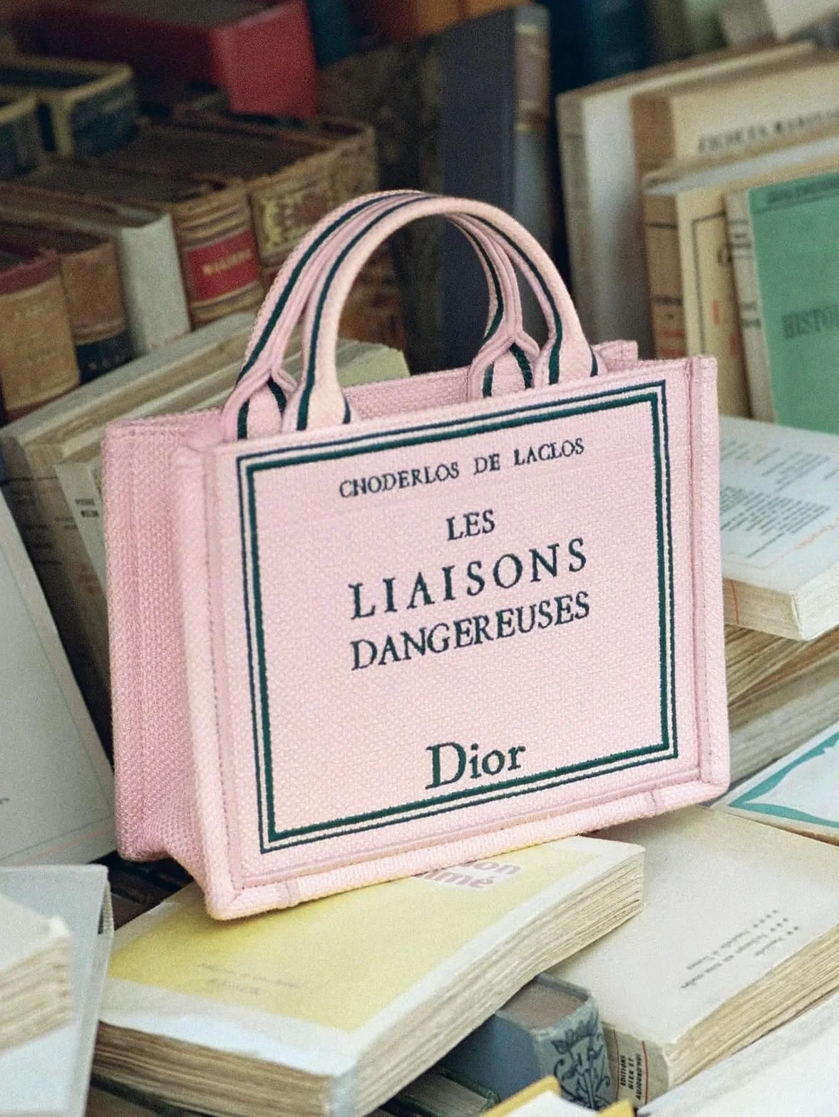 O que faz parar? A bolsa em um dos tons favoritos da estação em meio a diversos livros.