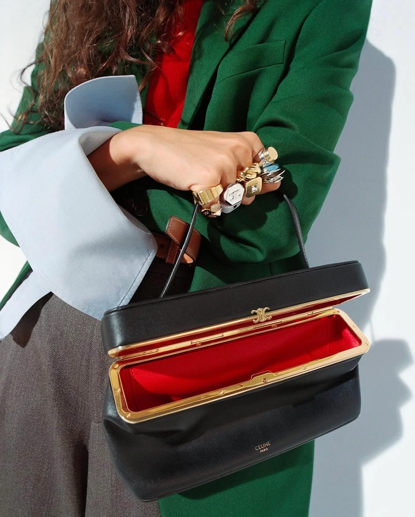 O que faz parar? Bolsa aberta com fundo vermelho. Contraste de cores. Excesso de anéis.